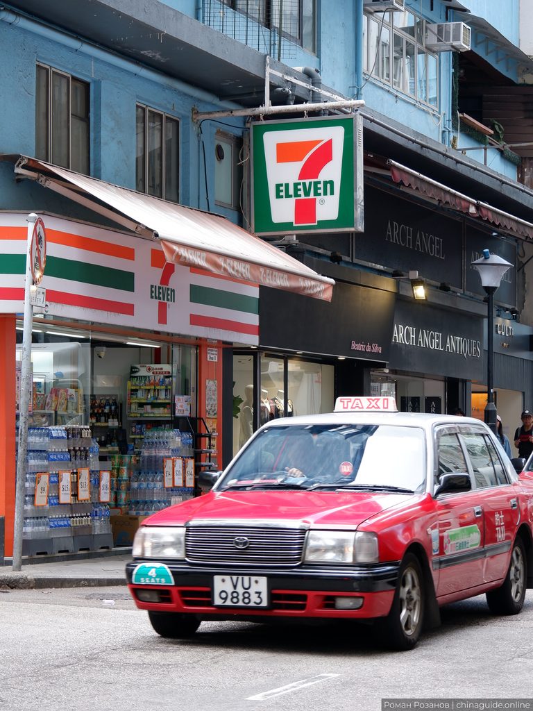 Красное такси Гонконга у магазина 7-Eleven