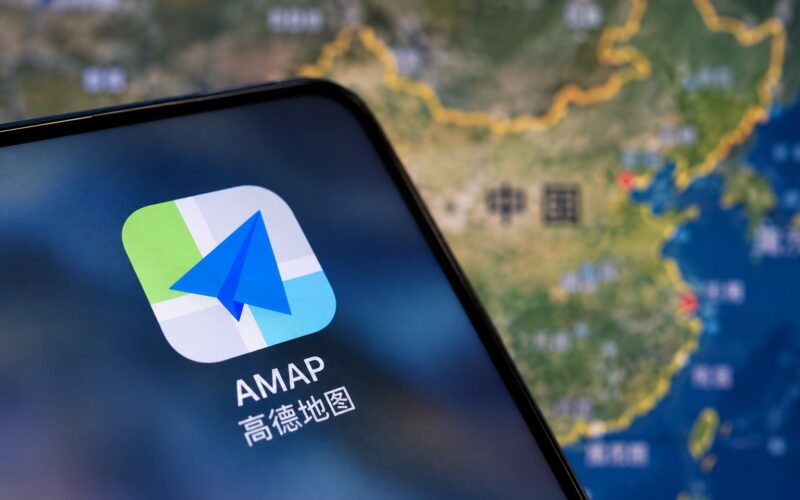 Приложение AMAP на экране смартфона перед картой Китая