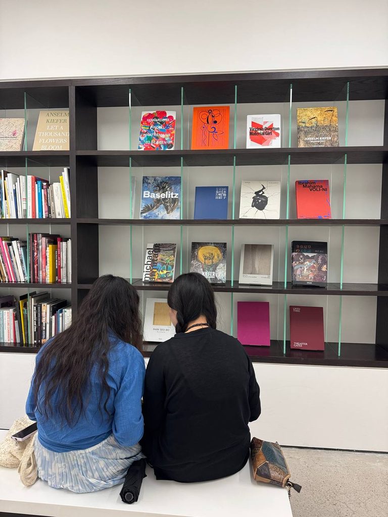Две женщины изучают книги на современной библиотечной полке